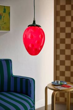 a red light hanging from a ceiling in a living room next to a blue chair