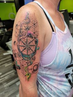 a woman with a colorful tattoo on her arm and shoulder is looking at the camera