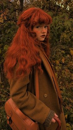 a woman with red hair is holding a brown purse