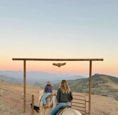 two people riding horses on top of a hill