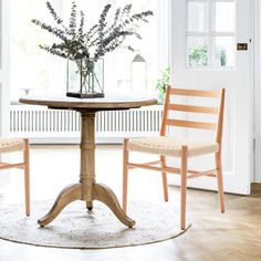 two chairs sitting at a table in front of a window with a potted plant on it