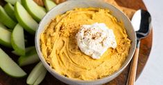 a bowl filled with hummus next to sliced green apples