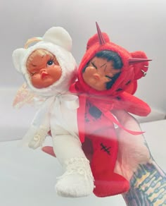 two dolls that are on top of each other in the palm of someone's hand