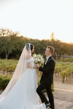 the bride and groom are walking together in front of some vineyards at their wedding