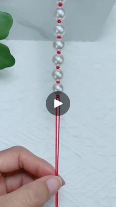 a person is holding a string with beads on it and making a bead chain