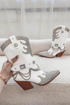 Made with white leather and adorned with crystal rhinestones and a silver chain, this statement boot is sure to turn heads. Heel height is 3.25" Rhinestone Boots With Round Toe For Rodeo, White Rhinestone Boots For Fall, White Leather Boots With Rhinestones, White High Ankle Moto Boots For Winter, Western Rhinestone Boots With Round Toe, Western Boots With Rhinestones And Round Toe, White Rhinestone Boots With Round Toe, Western Style White Ankle Boots, White High Heel Boots With Rhinestones