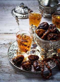 an assortment of teas and sweets on a tray with silver cups, spoons and sugar