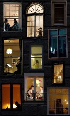 many windows with people sitting and standing in the window sill at night, all lit up