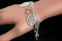 "A Pieta medal combined with a collection of silver plated Christian theme charms have been dispersed around a shimmering silver plated bracelet chain in this handmade charm bracelet. This religious charm bracelet is then completed with a lobster clasp and a 1/2 inch of chain at the end for adjustable sizing. ● Bracelet Styles ● Style #1 - Charms in this bracelet include a \"Christ Carrying the Cross\" charm, praying hands charm, a \"So Very Blessed\" charm, a Jesus fish charm, a \"Jesus loves y Vintage Silver Rosary Bracelet As Gift, Symbolic Silver Rosary Bracelet For Gifts, Symbolic Silver Rosary Bracelet Gift, Silver Symbolic Rosary Bracelet As Gift, Personalized Spiritual Silver Charm Bracelet, Spiritual Silver Rosary Bracelet With Charms, Symbolic Silver Rosary Bracelet, Nickel Free Silver Metal Rosary Bracelet, Silver Nickel-free Spiritual Charm Bracelet