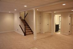 an empty living room with stairs leading up to the second floor and another door open