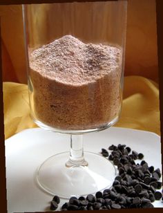 a glass with some food in it on a white plate next to black beans and a yellow cloth