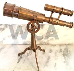 an antique brass telescope on a tripod stands on a marble surface with the word wpa above it