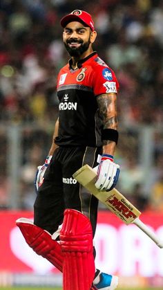 a man in black and red uniform holding a cricket bat