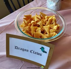 a glass bowl filled with cheetos sitting on top of a pink table cloth