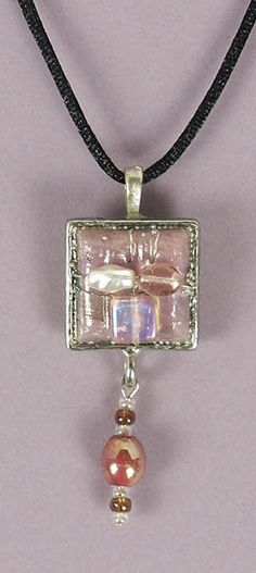 This pretty dimensional ENCASED JEWEL NECKLACE was handcrafted by Sandi Obertin.  It features a one (1) inch metal square that is embellished with pearl and glass components and a beaded dangle element.   The overall length of the pendant including the bale is approximately 2-1/2 inches .  It comes with a black satin cord and is ready to wear.  It would add the finishing touch a variety of clothing necklines and colors. Silver Jewelry With Square Pearl Pendant, Square Metal Necklace For Gift, Square Metal Necklaces For Gifts, Adjustable Silver Square Jewelry, Adjustable Square Silver Jewelry, Elegant Soldered Jewelry With Square Pendant, Unique Nickel-free Rectangular Jewelry, Unique Nickel Free Rectangular Jewelry, Handmade Metal Square Pendant Jewelry