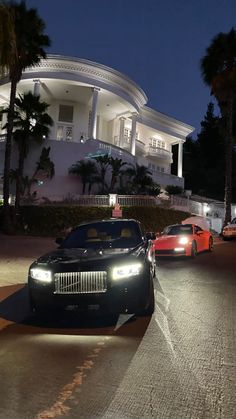 two cars parked in front of a mansion at night