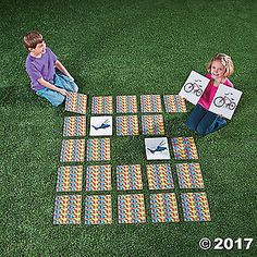 two children sitting on the grass with their paper cut out to look like an airplane