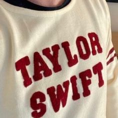 a close up of a person wearing a sweater with the word taylor swift on it