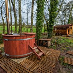 a hot tub sitting on top of a wooden deck next to trees and grass covered ground