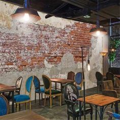 the interior of a restaurant with blue chairs and wooden tables, brick wall behind it