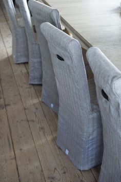 the chairs are lined up on the wooden floor near the table and chair cushions in front of them