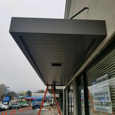 a store front with construction tape on the side and cars parked in the parking lot