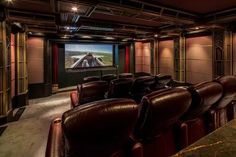 an empty theater with leather seats and a projector screen on the wall behind it