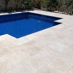 an empty swimming pool in the middle of a backyard with concrete pavers and landscaping