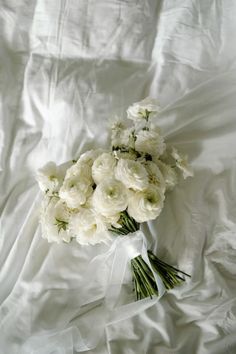 a bouquet of white flowers sitting on top of a white bed sheet covered in sheets