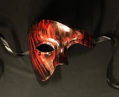 This Phantom mask is hand painted in a sold black then brushed red to give an abstract look. Mask is fully sealed and has a nice gloss look, Great for any Masquerade event or mask costume party! Size 6.5"W x 5.5"H. Color red and black. Red Masks And Prosthetics For Costume Party And Carnival, Artistic Red Masks And Prosthetics For Costume Party, Red Masks And Prosthetics For Mardi Gras Costume Party, Red Masks And Prosthetics For Mardi Gras Masquerade, Artistic Red Masks For Costume Party, Artistic Red Mask For Costume Party, Red Venetian Masks And Prosthetics For Costume Party, Red Masquerade Mask Men, Black Halloween Masks As Gifts