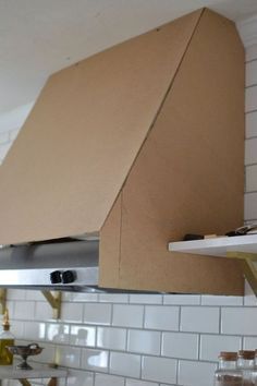 an open cardboard box on the hood of a stove in a kitchen with white tile walls