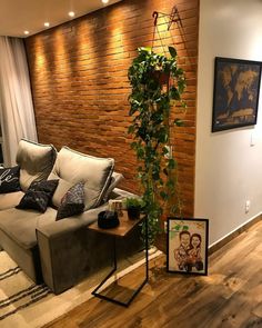 a living room filled with furniture and a tall plant next to a wall mounted tv