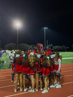 a group of cheerleaders huddle together at the end of a race track