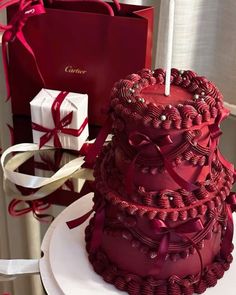 a red cake sitting on top of a white plate next to a box and candle