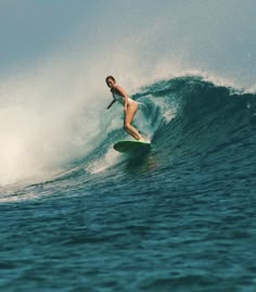 a man riding a wave on top of a surfboard in the ocean with blue water