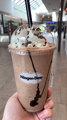 a hand holding up a chocolate drink with whipped cream and chocolate sprinkles