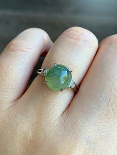 a woman's hand with a ring on it and a green stone in the middle