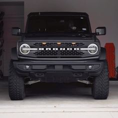 the front end of a black truck parked in a garage