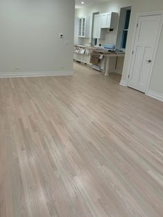 an empty room with hard wood flooring and white cabinetry in the back ground