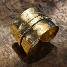 This unique and cool fold-formed brass wide cuff bracelet will always be the center of attention. Many of our designs are inspired by our fascination with the ancient cultures of the world, and this particular bracelet was inspired by the culture and lifestyle of the Vikings! This brutalist unisex cuff bracelet is made of brass. It is hammered, fold-formed, textured and polished entirely by hand in our studio. This handmade cuff bracelet is perfect for both women and courageous men... Its width is 4 cm. This cuff is adjustable, it can easily be squeezed for a tight fit or pried open for a looser fit. But even so, for its length, please select your size (considering the size of your wrist circumference) via the drop-down menu so that we can precisely prepare it for you.  Every piece in our Luxury Bronze Brass Bracelets, Luxury Bronze Cuff Bracelet As Gift, Gold Brass Wide Band Cuff Bracelet, Gold Brass Cuff Bracelet With Wide Band, Gold Wide Band Cuff Bracelet In Brass, Unique Gold Wide Band Cuff Bracelet, Unique Gold Wide Band Bracelet, Handmade Gold Cuff Bracelet With Wide Band, Handmade Wide Band Gold Cuff Bracelet