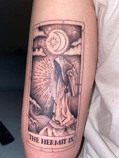 a tattoo on the arm of a person with a tarot card in front of them