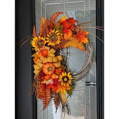 a wreath with sunflowers and fall leaves on the front door