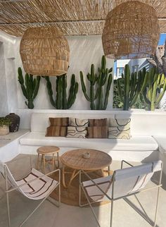 an outdoor living area with wicker furniture and large cactus hanging over the seating area