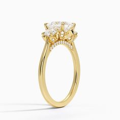 a yellow gold engagement ring with an oval cut diamond surrounded by smaller round brilliant diamonds