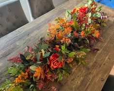 a wooden table topped with lots of different types of flowers and greenery on top of it