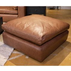 a brown leather ottoman sitting on top of a rug