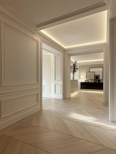 an empty room with wooden floors and white walls, in the middle of a hallway