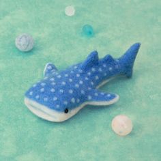 a blue and white toy shark laying on top of a green surface