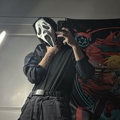 a man wearing a mask holding up a cell phone