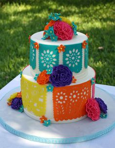 a multi - tiered cake decorated with flowers and crochets on a table